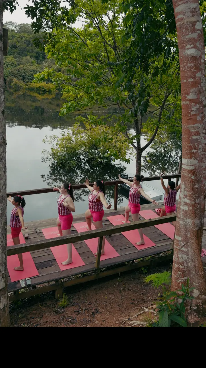 Mulheres praticando yoga em um deque de madeira à beira do rio
