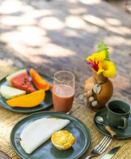 Café da manhã com frutas, tapioca, suco e café sobre a mesa