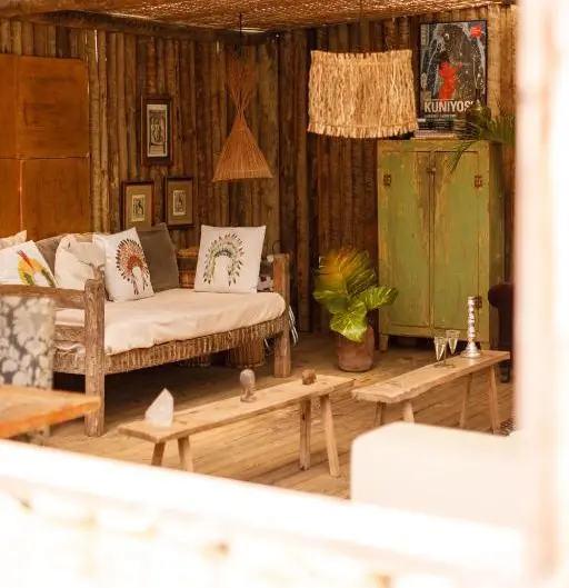 Lounge rústico da pousada com sofá de madeira, almofadas e plantas