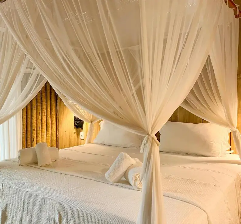Quarto da pousada com cama de dossel e cortinas brancas
