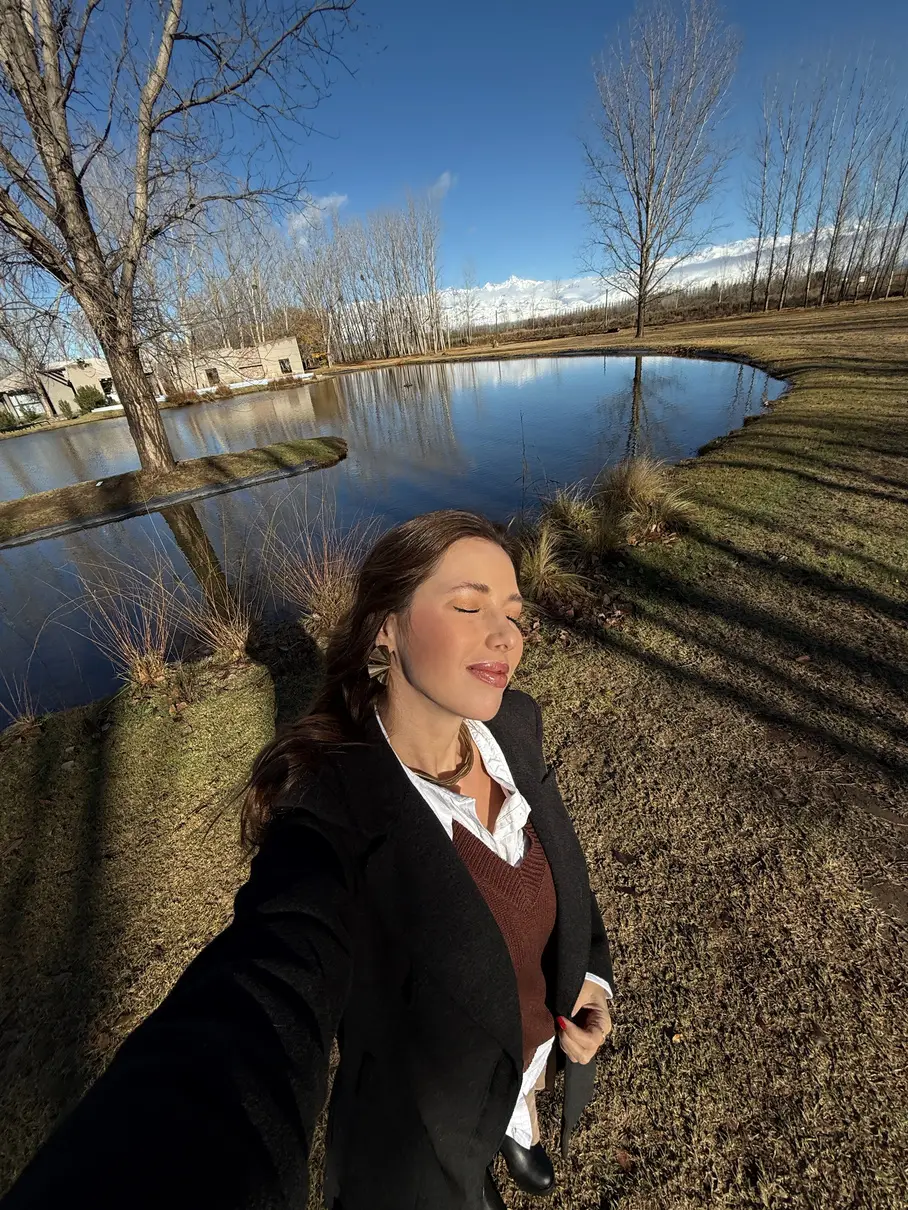 Mulher de olhos fechados tomando sol à beira de um lago