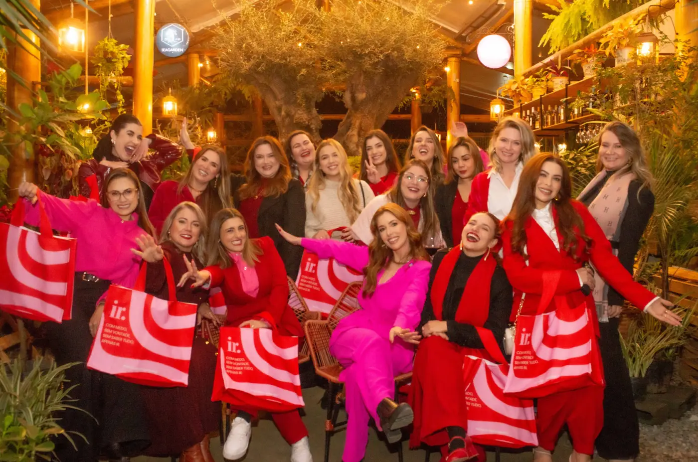Grupo de Donas vestidas de vermelho e rosa posando juntas em um evento presencial