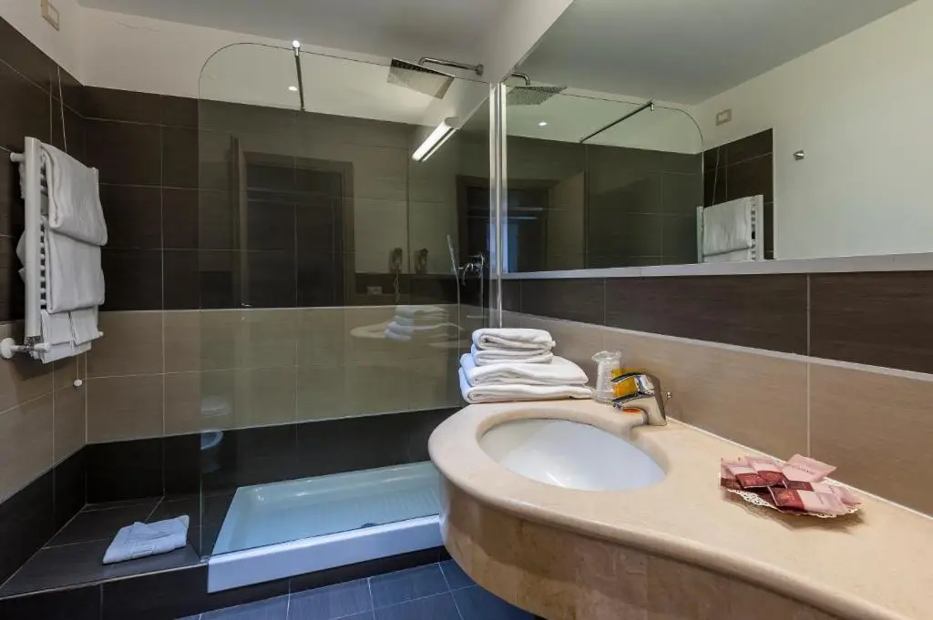 Banheiro do hotel com bancada de mármore e box de vidro