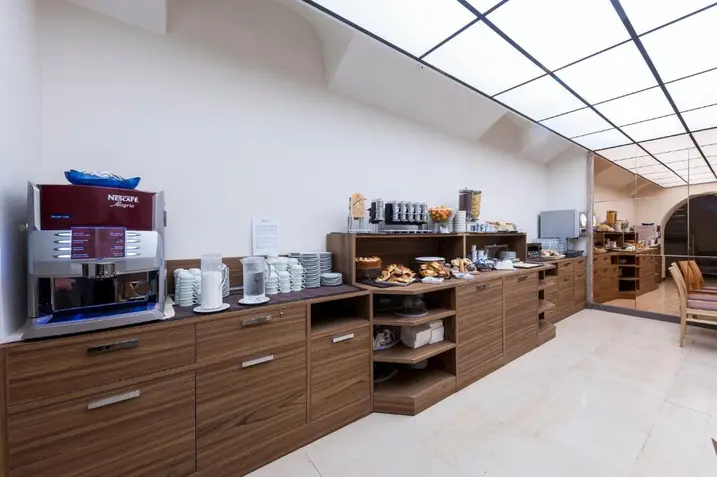 Salão de café da manhã do hotel com bufê de pães, doces e bebidas