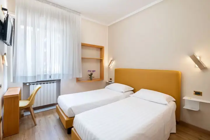 Quarto do hotel com duas camas de solteiro e cabeceira amarela