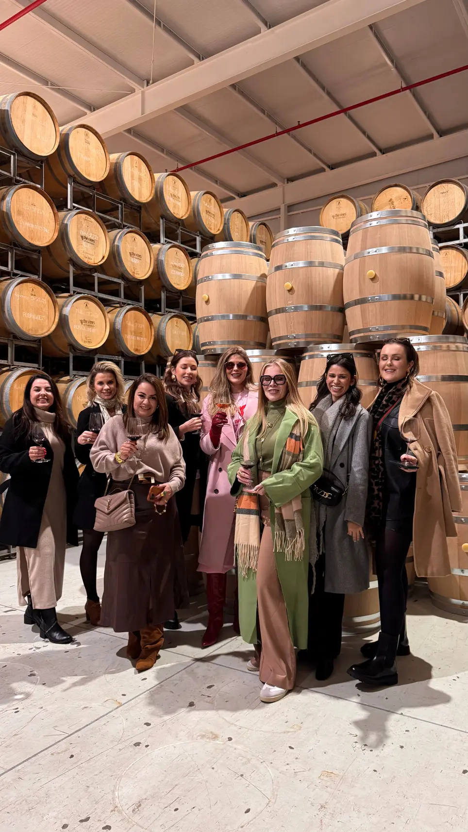 Grupo de Donas sorrindo na cave de uma vinícola, entre barris de carvalho