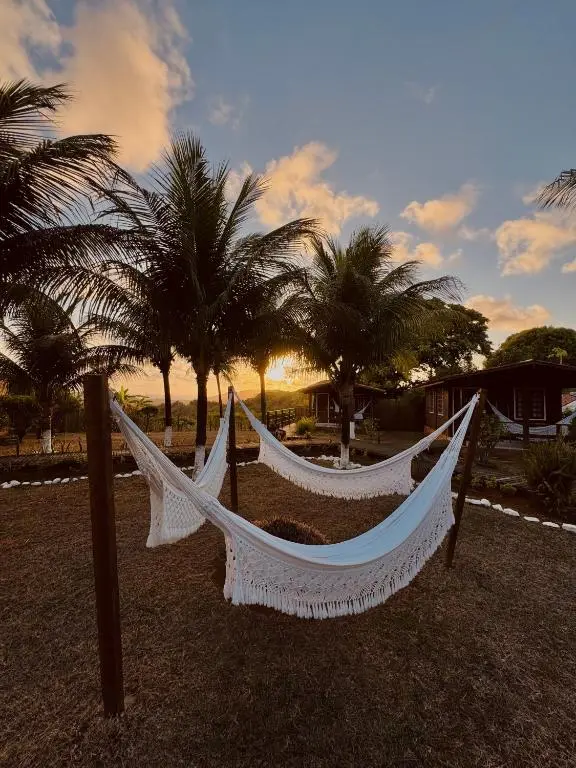 Redes brancas entre coqueiros no jardim da pousada ao entardecer