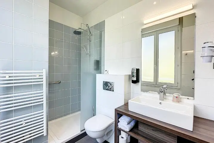 Banheiro do hotel com box de vidro e pia