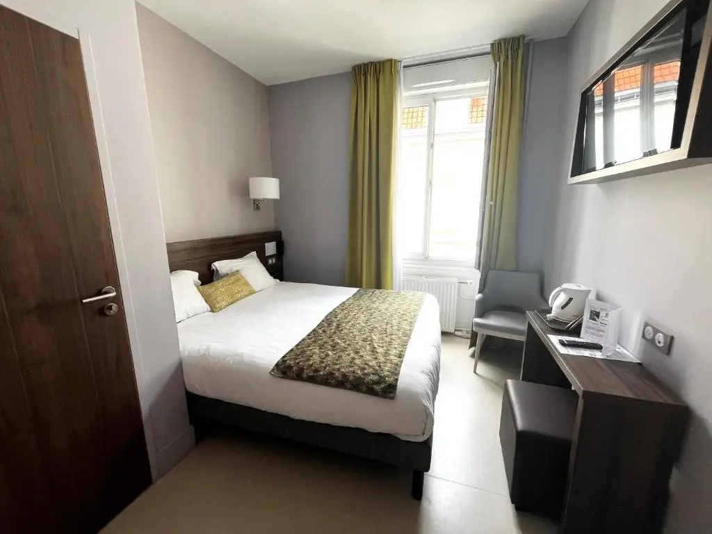 Quarto do hotel com cama de casal, poltrona e janela ampla